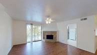 Located at 2610 Lakehill Ln in Carrollton, TX, this two-story home offers a well-organized layout across two floors. The main living area immediately impresses with rich hardwood flooring, a ceiling fan light fixture, and a striking corner brick fireplace with a white-trimmed mantel surround that serves as a focal point of the room. Large sliding glass doors flood the space with natural light and open to a private balcony overlooking mature trees, creating a seamless indoor-outdoor connection. The kitchen is outfitted with white cabinetry extending to the ceiling, ample counter space, tile flooring, and white appliances including an electric range with overhead microwave. A carpeted staircase connects the two floors, with the entry level also featuring tile flooring near the front entrance. The upper level includes generously sized bedrooms with plush carpet, ceiling fans, and windows that bring in natural greenery views. Bathrooms are clean and functional, with one featuring a full tub and shower combo, white tile surround, vanity with mirror, and tile floors. An additional half or water closet provides added convenience. Throughout, the home maintains a bright, neutral palette that enhances the sense of openness across both levels.