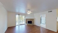 Located at 2610 Lakehill Ln in Carrollton, TX, this two-story home offers a well-organized layout across two floors. The main living area immediately impresses with rich hardwood flooring, a ceiling fan light fixture, and a striking corner brick fireplace with a white-trimmed mantel surround that serves as a focal point of the room. Large sliding glass doors flood the space with natural light and open to a private balcony overlooking mature trees, creating a seamless indoor-outdoor connection. The kitchen is outfitted with white cabinetry extending to the ceiling, ample counter space, tile flooring, and white appliances including an electric range with overhead microwave. A carpeted staircase connects the two floors, with the entry level also featuring tile flooring near the front entrance. The upper level includes generously sized bedrooms with plush carpet, ceiling fans, and windows that bring in natural greenery views. Bathrooms are clean and functional, with one featuring a full tub and shower combo, white tile surround, vanity with mirror, and tile floors. An additional half or water closet provides added convenience. Throughout, the home maintains a bright, neutral palette that enhances the sense of openness across both levels.