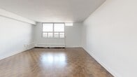 Located on the 15th floor at 2450 Weston Road in Toronto, this two-bedroom, one-bathroom unit offers a well-organized layout across a single floor. The modern kitchen is a standout feature, equipped with stainless steel appliances including a French door refrigerator, electric range, built-in microwave, and dishwasher. Crisp white shaker cabinetry, a light blue subway tile backsplash, gleaming tile flooring, and a dark-topped breakfast peninsula add both style and functionality to the space.

The open-concept kitchen flows into a generously sized living room, where classic parquet hardwood flooring adds warmth and character throughout. Large windows allow abundant natural light to fill the living area and offer elevated views of the surrounding cityscape.

Both bedrooms continue the parquet flooring aesthetic and are bright, thanks to sizable windows with city views. The primary bedroom features a mirrored sliding closet, while baseboard heating units are present throughout the unit. The full bathroom is finished with white subway tile surrounding a soaker tub, a dark wood vanity, and neutral floor tiles, creating a clean and timeless look. A hallway connects the main living areas to the bedrooms and bathroom, completing this well-appointed urban residence.