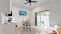 Located at 527 N Garden Ave in Clearwater, FL, this efficiently designed one-bedroom, one-bathroom single-floor unit offers a bright, modern living experience. The open-concept main area seamlessly integrates the living room, dining space, and kitchen into one cohesive layout. The kitchen features white shaker-style cabinetry, a stainless steel microwave, a compact sink, and clean white countertops, keeping the space functional yet visually uncluttered. Light wood-tone flooring runs throughout, complementing the crisp white walls and contributing to an airy, contemporary feel. A wall-mounted flat-screen TV, ceiling fan, and a sliding glass door leading to a private outdoor patio with seating round out the living and dining area, allowing natural light and outdoor views to fill the room.

The bedroom is a serene retreat with natural light filtering in through a window that frames lush greenery outside. It includes a dedicated closet for storage. The bathroom is a standout feature, finished with marble-style tile walls and flooring, a sleek frameless sliding glass shower enclosure, mosaic tile shower floor, and modern brushed nickel fixtures, delivering an upscale, spa-like atmosphere. Overall, the unit presents a clean, contemporary aesthetic well-suited to the sunny Clearwater lifestyle.