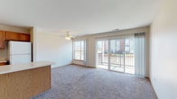 This single-floor unit offers a well-designed, open-concept layout that seamlessly connects the kitchen and living area. The living space is generously sized, finished with plush wall-to-wall carpeting and a ceiling fan with integrated lighting. Large sliding glass doors lead directly to a private balcony, flooding the interior with natural light and providing outdoor views of the surrounding neighborhood. A side window further enhances the brightness of the space.

The kitchen features warm oak cabinetry, a white electric range with an over-the-range microwave, a white refrigerator, and light-toned countertops. A peninsula island with additional cabinetry provides extra prep space and serves as a natural divider between the kitchen and living area.

The unit includes two carpeted bedrooms, each with windows that bring in natural light. One bedroom benefits from a double window arrangement, while the other offers a single window with outdoor views. Both rooms include closet access.

Two bathrooms serve the unit, each finished with light ceramic tile flooring, oak vanity cabinetry, white countertops, and neutral-toned walls. The layout also includes a dedicated entryway and walk-in closet, contributing to the overall functionality and livability of the space.