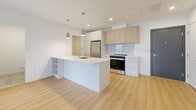 Located at 17 Place de la Triade in Pointe-Claire, Quebec, this well-appointed 2-bedroom, 2-bathroom unit with a den offers a thoughtfully designed layout with modern finishes throughout. Light hardwood flooring flows seamlessly across the entire space, complementing the clean white walls and creating a bright, airy atmosphere.

The heart of the unit is an open-concept kitchen, dining, and living area. The kitchen features a large central island with an undermount sink, stainless steel appliances including a refrigerator, range, and dishwasher, white lower cabinetry paired with warm wood-toned upper cabinets, and a classic subway tile backsplash. Pendant lighting adds a modern touch overhead. The open living area benefits from large sliding glass doors that lead to a private balcony, flooding the space with natural light.

Both bedrooms are generously sized with large windows offering views of the surrounding neighborhood. Three closets provide ample storage throughout the unit. The primary bathroom is finished with large-format tiles, a soaking tub with glass shower enclosure, and a warm wood vanity with white countertop. A second bathroom echoes the same refined aesthetic. A dedicated laundry room houses a full-sized washer and dryer, adding everyday convenience to this well-rounded home.