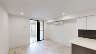 Located at 5695 Rue Saint-Jacques in the Notre-Dame-de-Grâce neighbourhood of Montréal, this efficiently designed single-floor unit offers a thoughtfully organized layout comprising a living room, kitchen, and bathroom. The open-concept main area seamlessly connects the kitchen and living space, finished with light wood-look flooring and clean white walls that enhance the sense of brightness throughout. A wall-mounted split air conditioning unit ensures year-round climate comfort. The contemporary kitchen is a standout feature, equipped with stainless steel appliances including a range, over-the-range microwave, and refrigerator, complemented by a dishwasher. Sleek two-tone cabinetry — dark wood lower units paired with glossy white upper cabinets — frames a striking dark chevron-patterned tile backsplash. A light-toned countertop with an undermount sink and matte black faucet completes the polished look. Recessed lighting throughout adds a modern, clean finish. The living area provides a versatile open space with a wall-mounted TV bracket ready for use. The bathroom delivers a refined aesthetic with floor-to-ceiling marble-effect wall tiles, a frameless sliding glass shower enclosure featuring a rain showerhead, and dark hardware accents that add a sophisticated contrast.