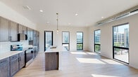 Located at 1301 Mulberry St in Des Moines, Iowa, this modern 2-bedroom, 2-bathroom residence offers a thoughtfully designed open-concept layout with contemporary finishes throughout. Light hardwood flooring flows through the main living areas, complementing the bright, neutral palette that defines the space.

The kitchen is a standout feature, showcasing rich dark-toned cabinetry extending to the ceiling for ample storage, stainless steel appliances, a white tile backsplash, quartz countertops, and a central island with a built-in sink. Elegant brass pendant lights add a refined touch overhead. The open living area is bathed in natural light through large black-framed windows that frame urban views of the Des Moines skyline. Exposed ductwork adds an industrial design element to the space.

The spacious primary bedroom features plush carpet, a ceiling fan, and a wall of large windows offering sweeping city views. The second bedroom is equally well-lit with its own window. Both bathrooms are finished with quartz-topped dark vanities, modern fixtures, and clean tile work, with one featuring a full soaking tub and shower combination. A dedicated closet provides additional storage. This residence combines modern urban design with functional, comfortable living.