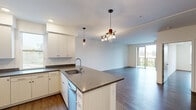 Located on Pacific Avenue in Santa Cruz, California, this modern 2-bedroom, 2-bathroom residence offers a well-designed, single-floor layout with contemporary finishes throughout. The open-concept kitchen and living area serves as the heart of the home, featuring a large center island with a dark quartz countertop and undermount sink, crisp white cabinetry extending to the ceiling, and a full suite of stainless steel appliances including a refrigerator, range, microwave, and dishwasher. Stylish pendant lighting illuminates the kitchen and flows into the bright, spacious living area, which is finished with wide-plank hardwood-style flooring. Sliding glass doors lead from the living room to a private balcony with pleasant outdoor views, filling the space with natural light. The generously sized primary bedroom includes a large walk-in closet with built-in shelving and its own dedicated bathroom access. The second bedroom is equally well-appointed, bathed in natural light from a large picture window with treetop views. Both bathrooms are clean and functional, featuring light wood-tone flooring and a shower-tub combination. A hallway connects all rooms seamlessly, with additional closet storage available. A wall-mounted mini-split system provides efficient climate control throughout.