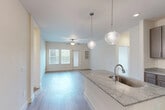 Located at 4770 Military Drive West in San Antonio, Texas, this well-designed 2-bedroom, 1-bathroom residence offers a thoughtfully laid-out single-floor plan with contemporary finishes throughout. The open-concept kitchen and living area serves as the heart of the home, featuring a large center island topped with granite countertops and an integrated sink, complemented by elegant pendant lighting. Dark taupe cabinetry, stainless steel appliances — including a refrigerator and microwave — and a black range complete the kitchen. Wood-style plank flooring flows seamlessly throughout the entire residence, lending a clean, cohesive aesthetic. The bright and airy living room benefits from multiple windows with blinds, a ceiling fan, and a built-in shelving nook, creating an inviting and functional gathering space. Both bedrooms are generously sized, each featuring ceiling fans, natural light from windows, and easy access to hallways and closets. The primary bedroom connects directly to the full bathroom, which offers a dual-sink vanity with granite countertops, matching dark cabinetry, a soaking tub, and direct access to a walk-in closet. The overall design is clean, modern, and move-in ready.