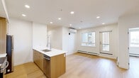 Located at 110 Lucas Street NW in Calgary, this well-appointed 3-bedroom, 2-bathroom unit offers a thoughtfully designed single-floor layout with modern finishes throughout. Light hardwood-style flooring runs continuously across the entire space, creating a cohesive and bright aesthetic.

The open-concept kitchen serves as the heart of the unit, featuring two-tone cabinetry — crisp white upper cabinets paired with warm wood-grain lower cabinets — complemented by white quartz countertops, a central island with an undermount sink, and stainless steel appliances including a refrigerator and electric range. Recessed lighting illuminates the space efficiently.

The primary bedroom is generously sized, while the two additional bedrooms offer flexible use with clean white walls and ample natural light. Double closet doors provide practical storage in the bedrooms. Both bathrooms are finished with wood-tone vanity cabinetry, white countertops, and clean tile surrounds — one featuring a full soaker tub and shower combo.

A dedicated in-unit laundry area houses a stacked washer and dryer set. A hallway connects all rooms seamlessly. The unit also includes access to a private balcony overlooking the surrounding developing community. Clean lines, neutral tones, and contemporary finishes define the overall ambiance of this functional and modern Calgary residence.