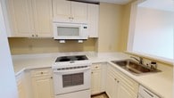 This single-floor residence features 2 bedrooms and 2 bathrooms, offering a straightforward and functional layout designed for comfortable everyday living. The kitchen is a standout feature, equipped with white cabinetry that extends to the upper walls for generous storage capacity. White appliances — including an electric range, an over-the-range microwave, and a stainless steel sink — are neatly integrated into the space. Light countertops provide ample workspace, and the clean, neutral color palette of soft yellow walls and white finishes lends the kitchen a bright, tidy feel. Natural light filters in through a window near the sink, enhancing the overall sense of openness. The cabinetry features classic raised-panel doors with gold-toned hardware, adding a subtle traditional touch to the room. The overall design of the home prioritizes practicality and ease of use, with a cohesive aesthetic carried throughout. The two bedrooms provide comfortable private retreats, while the two full bathrooms ensure convenience for residents and guests alike. This well-maintained, single-level home is well-suited for those seeking an accessible, move-in-ready space with consistent, clean finishes.