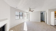 Located at 6317 Shanda Dr in Raleigh, NC, this single-story home offers four bedrooms and two bathrooms within a well-organized floor plan. The living room serves as a central gathering space, highlighted by a white brick fireplace, a ceiling fan with light fixture, soft carpeting, and a textured ceiling. Natural light pours in through windows overlooking a private deck, accessible via a glass-panel door. The kitchen is outfitted with rich dark cabinetry, stainless steel appliances including a refrigerator and electric range, light countertops, and durable hardwood-style flooring. A large window brightens the adjacent dining area. The bedrooms feature plush carpeting and generous closet space, including a walk-in closet with dual hanging rods. The primary bedroom offers a comfortable, well-proportioned layout. Both bathrooms are finished with dark vanity cabinetry, light countertops, framed mirrors, and clean white tub-shower surrounds. Additional rooms with hardwood-style flooring and large windows provide flexible living options. Throughout the home, a neutral color palette and consistent finishes create a cohesive and functional living environment.