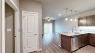 Located at 4401 W Oak St in Rogers, Arkansas, this 1-bedroom, 1-bathroom unit offers a thoughtfully designed single-floor layout that maximizes functionality and comfort. Wood-style flooring runs throughout the entire space, providing a cohesive and modern aesthetic.

The open-concept kitchen and living area forms the heart of the unit. The kitchen is outfitted with rich, dark wood cabinetry, stainless steel appliances including a refrigerator, range, and microwave, and a granite-topped island with an undermount sink. Pendant lighting above the island adds a refined touch. The living area benefits from a sliding glass door with vertical blinds that invites natural light and provides outdoor access, complemented by a ceiling fan overhead.

The bedroom is a comfortable, well-proportioned room featuring its own ceiling fan, a large window for natural light, and direct access to the bathroom. The bathroom is spacious and includes a dual-sink vanity with white countertops, dark wood cabinetry, and wood-style flooring. A dedicated closet with rod and shelf storage is accessible directly from the bathroom, offering convenient organization. The clean, neutral color palette throughout the unit creates a bright and welcoming atmosphere.