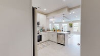 Located at 69 E Central St in Natick, MA, this well-appointed 2-bedroom, 2-bathroom residence offers a thoughtfully designed single-floor layout. The open-concept kitchen and living area serves as the heart of the home, featuring a sleek white shaker-style kitchen with stainless steel appliances, subway tile backsplash, pendant lighting, and ample cabinetry. Light wood-style flooring flows throughout the main living areas, enhancing the bright, airy atmosphere. The living room is a standout, boasting a curved bay of oversized windows that flood the space with natural light and frame sweeping views of downtown Natick. Both bathrooms are finished with crisp white cabinetry, tile flooring, and modern fixtures; one includes a glass-enclosed walk-in shower. The generously sized primary bedroom offers a tranquil retreat with carpeted flooring and recessed lighting, while the second bedroom features large windows with neighborhood views. A dedicated office and closet provide additional functionality. Warm neutral tones and recessed lighting throughout create a cohesive, modern ambiance that is both inviting and practical.