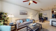 This single-floor residence offers a thoughtfully designed layout that balances comfort and functionality throughout. The living room serves as the heart of the home, featuring vaulted ceilings, a ceiling fan, and plush carpeting. Natural light filters in through large windows, creating a bright and welcoming atmosphere, while a glass-top coffee table and neutral-toned furnishings contribute to the space's relaxed, contemporary feel. A dedicated dining area sits just off the living room, providing a seamless transition for entertaining.

The kitchen is well-equipped with rich dark wood cabinetry, granite countertops, tile flooring, and a full suite of black appliances including a refrigerator, range, and microwave. A peninsula with an undermount sink adds both prep space and a casual dining option. Pendant and track lighting complete the kitchen's polished look.

The bedroom is generously sized with carpet flooring, a ceiling fan, and French doors that open to a private outdoor area. A built-in desk nook and ample dresser space add practical storage and workspace. The full bathroom features tile flooring, a soaking tub with tiled surround, and a dark wood vanity with granite countertop. An in-unit laundry area with full-size washer and dryer rounds out the home's convenient amenities.