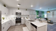 This thoughtfully designed 1-bedroom, 1-bathroom residence offers a functional and stylish layout across a single floor. The open-concept kitchen and living area serves as the heart of the space, where a modern kitchen showcases crisp white shaker cabinetry, quartz countertops, stainless steel appliances including a gas range, microwave, dishwasher, and refrigerator, and a peninsula with bar seating. Tall upper cabinets with frosted glass panels and a built-in wine rack add both storage and character. Wood-look flooring flows throughout the main living area, complementing the clean, contemporary aesthetic. The living room features a bold green accent wall, large windows with plantation shutters that invite natural light, and ample space for comfortable seating and entertainment. The bedroom offers plush carpeting, a ceiling fan, natural light from dual windows, and a sliding barn door leading to a walk-in closet. The bathroom is finished with wood-look tile flooring, a single vanity with a large mirror, and understated, neutral tones. Recessed lighting throughout and a cohesive neutral color palette give the entire residence a bright, modern, and welcoming ambiance.