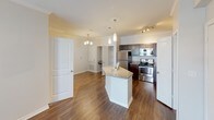 This single-floor residence offers a thoughtfully designed layout that balances comfort and functionality. Rich, dark hardwood-style flooring flows seamlessly throughout the main living areas, complementing the neutral-toned walls and crisp white trim and baseboards that frame each room.

The open-concept living area is bright and welcoming, featuring crown molding, a ceiling fan with light fixture, and access to a glass-paned exterior door that allows natural light to pour in. The space connects fluidly to the kitchen, which serves as a central hub of the home. The kitchen is equipped with dark espresso cabinetry, granite-style countertops, a center island with additional prep space, stainless steel appliances including a refrigerator, range, microwave, and dishwasher, and pendant lighting overhead that adds a refined touch.

The bedroom continues the warm flooring aesthetic and includes a ceiling fan, a window with blinds for natural light and privacy, and direct access to a closet. The bathroom features large-format tile surrounding the tub and shower area, conveying a clean and modern aesthetic. Throughout the space, the consistent use of neutral tones, quality finishes, and practical design elements create a cohesive and inviting atmosphere.