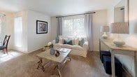 This single-floor residence offers a thoughtfully arranged layout with a range of functional and comfortable spaces. The living room serves as the heart of the home, featuring plush carpeting, neutral walls, and a large window dressed with sheer and panel curtains that invite natural light and views of surrounding greenery. Adjacent to the living area, the dining space accommodates a cozy table for two beneath a ceiling fan, with sliding glass door access that further brightens the room.

The kitchen is well-equipped, featuring warm knotty wood cabinetry, speckled granite-style countertops, tile flooring, and a full suite of black appliances including a range, microwave, and refrigerator. A pass-through counter connects the kitchen to the main living area, enhancing the open feel.

The primary bedroom is carpeted and serene, with a window allowing natural light and outdoor views. A second bedroom provides versatile space, also carpeted and suitable for various uses. Both bathrooms are finished with tile flooring, wood vanities topped with granite-style counters, and tub-shower combinations.

A dedicated in-unit laundry area houses a full-size washer and dryer, adding significant convenience to daily living. Throughout, the home maintains a clean, neutral palette and consistent finishes.