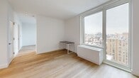 Located at 644 E 14th Street in Manhattan's vibrant East Village neighborhood, this thoughtfully designed studio offers a clean, modern aesthetic with high-end finishes throughout. Light hardwood flooring runs continuously across the open living space, lending warmth and cohesion to the layout.

The kitchen is a standout feature, outfitted with white flat-front cabinetry, warm wood upper cabinets with under-cabinet lighting, a white quartz countertop, a brushed gold faucet with a stainless steel sink, and a professional-grade stainless steel range. A built-in microwave and full-height pantry cabinetry complete the well-appointed cooking space.

The bathroom showcases refined finishes including herringbone-patterned tile flooring, full-height wood-toned wall tile, a floating wood vanity with an integrated sink, a sleek mirror with overhead lighting, and a full soaking tub with a rainfall shower — creating a serene, spa-inspired atmosphere.

Large floor-to-ceiling windows flood the living area with natural light and frame sweeping elevated views of the Manhattan skyline and surrounding East Village rooftops. The space also includes two closets, a dedicated laundry area, and a utility room, maximizing functionality. The overall design is clean, minimal, and move-in ready.