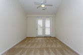 This single-floor residence offers a thoughtfully designed open-concept layout that seamlessly connects the living and kitchen areas. The spacious living room features soft carpeting, a ceiling fan, and a smooth flow into the kitchen, which serves as the heart of the home. The kitchen is outfitted with rich wood cabinetry, granite countertops, a tiled backsplash, stainless steel appliances including a refrigerator, electric range, and built-in microwave, plus a generous island with an undermount sink — all set atop warm hardwood-style flooring. Crown molding and track lighting add a polished touch to the space. The bedrooms are carpeted and generously sized, with vaulted ceilings, ceiling fans, and large windows that invite natural light and exterior views. The primary bedroom features a walk-in closet with built-in shelving and access to a private area, while additional bedrooms offer comfortable proportions with ample natural light. The bathroom is finished with wood-style flooring, a granite-topped vanity with warm wood cabinetry, and a full tub-shower combination with tile surround. Throughout, the home maintains a neutral, inviting palette with clean lines and quality finishes that create a comfortable and functional living environment.