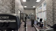 The fitness center at 480 Bedford Rd in Chappaqua, NY is a well-appointed, single-floor exercise facility designed to support a comprehensive workout experience. The space is defined by its striking textured brick-style walls rendered in tones of grey and charcoal, lending an industrial-chic aesthetic balanced by elegant architectural details. Large, multi-pane windows and a set of classic French doors flood the interior with natural light and offer views of an outdoor courtyard, creating an open and inviting atmosphere.

The flooring throughout features a multi-toned carpet tile with a subtle striped pattern, providing both durability and visual interest underfoot. The cardio zone is equipped with Cybex-brand treadmills, elliptical trainers, and stationary bikes, positioned alongside wall-mounted flat-screen televisions for entertainment during workouts. A dedicated strength training area offers a full rack of dumbbells in graduated weights, an adjustable workout bench, and a cable/multi-station strength machine. Additional functional fitness equipment, including resistance accessories, rounds out the offerings.

Glass partition doors connect the fitness center to an adjacent lounge or common area, allowing for visual connectivity while maintaining acoustic separation. The combination of quality equipment, abundant natural light, and refined design details makes this fitness center a functional and aesthetically elevated space.