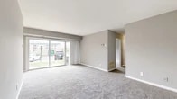 Located at 3822 Regency Pkwy in Suitland, Maryland, this single-floor, 2-bedroom, 2-bathroom residence offers a practical and comfortable layout. The living area is generously proportioned, featuring soft carpeting underfoot and neutral gray walls that lend a clean, understated aesthetic. A set of sliding glass doors spans much of one wall, flooding the space with natural light while providing views of the surrounding outdoor area. A chandelier accent in the adjoining dining area adds a subtle decorative touch.

The galley-style kitchen is efficiently designed, featuring warm wood cabinetry, light countertops, tile flooring, and white appliances including a gas range and refrigerator. A washer is conveniently integrated within the kitchen space. The two bathrooms are functional and tidy, with tile flooring, neutral walls, and standard fixtures including a tub-shower combination in one.

Both bedrooms are carpeted and bathed in natural light from windows overlooking the exterior. The primary bedroom is spaciously sized, while each bedroom benefits from dedicated closet space, including a walk-in closet with built-in shelving and hanging rods. Two hallways connect the rooms, contributing to a smooth, organized flow throughout the residence.