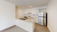 Located at 835 Van Buren in Fort Wayne, Indiana, this one-bedroom, one-bathroom unit offers a well-designed layout across a single floor, making efficient use of its compact footprint. The kitchen is a standout feature, outfitted with crisp white shaker cabinetry, quartz countertops, a subway tile backsplash, stainless steel appliances including a refrigerator and range, and a peninsula that provides additional prep and seating space. Recessed lighting and clean finishes give the kitchen a bright, contemporary feel. The bedroom is a comfortable, well-proportioned room with speckled low-pile carpeting, a built-in closet with panel doors, a wall-mounted mini-split HVAC unit, and a wood-trimmed window that allows natural light and views of the surrounding cityscape. The bathroom is elegantly appointed with large-format marble-look tile lining the tub and shower surround, built-in niche shelving, brushed bronze fixtures, and terrazzo-style flooring that ties the space together. A highlight of the property is the generous outdoor deck, constructed with a classic brick exterior and metal railing, offering sweeping views of the Fort Wayne skyline, neighborhood rooftops, and lush treetops — ideal for outdoor relaxation or entertaining.