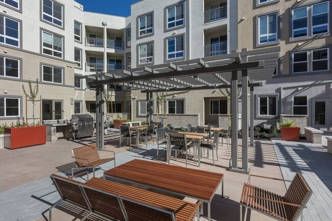 Outdoor dining area with BBQ stations and shaded seating at Aster Apartments in Dublin, CA. - Aster