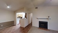 Located along US Highway 98 in Daphne, Alabama, this single-floor residence offers a thoughtfully arranged layout that balances comfort and functionality. The main living area is highlighted by vaulted ceilings that create an open, airy atmosphere, and a classic wood-framed fireplace with a tiled hearth serves as a natural focal point of the room. Warm hardwood flooring extends throughout the primary living space, transitioning to carpet in select areas for added comfort. A pass-through opening connects the living area to the kitchen, maintaining a sense of openness while defining each space. The kitchen features light wood cabinetry, a tile backsplash, and white appliances, offering a clean and practical cooking environment. Neutral wall tones throughout contribute to a bright, welcoming ambiance that makes the space feel open and easy to personalize. The single-floor design ensures convenient, accessible living, with each area flowing naturally into the next. This residence combines practical amenities with comfortable architectural details, making it a well-rounded home in the heart of Daphne.