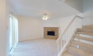 Located at 2610 Lakehill Ln in Carrollton, Texas, this two-story home offers a thoughtfully designed layout across two levels. The living room serves as the heart of the main floor, highlighted by a striking corner brick fireplace framed by a vaulted white mantel surround, plush carpeting, and a ceiling fan with light fixture. A staircase with white railings and carpeted treads connects the two floors seamlessly. Adjacent to the living area, the dining space features pendant lighting and opens directly to the kitchen through a pass-through counter. The kitchen is equipped with white cabinetry featuring beadboard detailing, light stone countertops, tile flooring, and white appliances including a range, built-in microwave, and dishwasher. The bathrooms are finished with tile flooring, white vanity cabinetry, stone countertops, and ornate framed mirrors. One bathroom includes a tub and shower combination alongside a medicine cabinet. Upstairs, the bedrooms are carpeted and bright, benefiting from natural light through windowed views of surrounding greenery. At least one bedroom includes a spacious walk-in closet with built-in shelving. Textured ceilings are consistent throughout, and ceiling fans are present in multiple rooms, contributing to a comfortable, functional living environment.