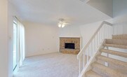 Located at 2610 Lakehill Ln in Carrollton, Texas, this two-story home offers a thoughtfully designed layout across two levels. The living room serves as the heart of the main floor, highlighted by a striking corner brick fireplace framed by a vaulted white mantel surround, plush carpeting, and a ceiling fan with light fixture. A staircase with white railings and carpeted treads connects the two floors seamlessly. Adjacent to the living area, the dining space features pendant lighting and opens directly to the kitchen through a pass-through counter. The kitchen is equipped with white cabinetry featuring beadboard detailing, light stone countertops, tile flooring, and white appliances including a range, built-in microwave, and dishwasher. The bathrooms are finished with tile flooring, white vanity cabinetry, stone countertops, and ornate framed mirrors. One bathroom includes a tub and shower combination alongside a medicine cabinet. Upstairs, the bedrooms are carpeted and bright, benefiting from natural light through windowed views of surrounding greenery. At least one bedroom includes a spacious walk-in closet with built-in shelving. Textured ceilings are consistent throughout, and ceiling fans are present in multiple rooms, contributing to a comfortable, functional living environment.