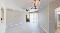Located in Phoenix, AZ, this thoughtfully designed single-story home offers three bedrooms and two bathrooms across a efficient, well-organized floor plan. The living and dining area features light wood-style flooring, a striking globe pendant light fixture, a ceiling fan, and sliding glass doors fitted with vertical blinds that invite natural light and provide outdoor access. An arched pass-through window connects the dining area to the kitchen, adding a charming architectural detail. The kitchen is outfitted with white cabinetry, light countertops, a subway tile backsplash, stainless steel appliances including a range and microwave, and a skylight that brightens the space naturally. The bedrooms offer plush carpeting and ceiling fans, with the primary bedroom providing a comfortable, generously sized retreat. The two bathrooms are finished in clean white tones, featuring tub-shower combinations with gold or brushed nickel fixtures, wood-style flooring, and ample vanity storage. A dedicated laundry room with a full-size washer and dryer adds everyday convenience. Neutral gray walls throughout the home create a cohesive, modern aesthetic that complements the bright, airy atmosphere of the space.