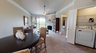 This single-floor residence offers a thoughtfully designed layout that seamlessly connects the living, dining, and kitchen areas. The living room is a standout space, highlighted by a tray ceiling with crown molding, a ceiling fan, and a fireplace framed by a white surround. Large sliding glass doors lead to a private balcony, flooding the room with natural light and offering sweeping views of a lush, tree-covered hillside. Soft carpeting and neutral wall tones create a warm, inviting ambiance throughout.

The adjacent dining area flows naturally from the living space, making it well-suited for entertaining. The kitchen is outfitted with dark espresso cabinetry, granite-style countertops, stainless steel appliances including a range, microwave, and dishwasher, and hardwood-style flooring.

The primary bedroom is generously sized with vaulted ceilings, plush carpeting, and access to a walk-in closet. Its en-suite bathroom features dual sinks set in dark cabinetry with granite countertops, a large mirror, and hardwood-style flooring. A second bathroom includes a soaking tub with decorative red tile accenting. An additional bedroom provides ample space and natural light, completing this comfortable and refined residence.