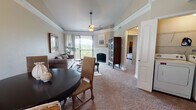 This single-floor residence offers a thoughtfully designed layout that seamlessly connects the living, dining, and kitchen areas. The living room is a standout space, highlighted by a tray ceiling with crown molding, a ceiling fan, and a fireplace framed by a white surround. Large sliding glass doors lead to a private balcony, flooding the room with natural light and offering sweeping views of a lush, tree-covered hillside. Soft carpeting and neutral wall tones create a warm, inviting ambiance throughout.

The adjacent dining area flows naturally from the living space, making it well-suited for entertaining. The kitchen is outfitted with dark espresso cabinetry, granite-style countertops, stainless steel appliances including a range, microwave, and dishwasher, and hardwood-style flooring.

The primary bedroom is generously sized with vaulted ceilings, plush carpeting, and access to a walk-in closet. Its en-suite bathroom features dual sinks set in dark cabinetry with granite countertops, a large mirror, and hardwood-style flooring. A second bathroom includes a soaking tub with decorative red tile accenting. An additional bedroom provides ample space and natural light, completing this comfortable and refined residence.