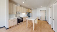 Located at 2260 Bohland Ave in Saint Paul, Minnesota, this one-bedroom, one-bathroom unit offers a practical and well-designed single-floor layout. The open-concept kitchen and living area serves as the heart of the space, featuring light maple cabinetry extending to the ceiling for generous storage, a white quartz island that doubles as a dining surface, and a full suite of stainless steel appliances including a refrigerator, electric range, built-in microwave, and dishwasher. Recessed lighting illuminates the kitchen, which is finished with light hardwood-style flooring that adds warmth and continuity throughout the main living area. The bedroom is carpeted for comfort and features neutral walls, bold dark baseboards, and a dedicated closet with built-in shelving for organized storage. A secondary closet provides additional storage within the unit. The bathroom is thoughtfully appointed with light wood vanity cabinetry, a tall storage tower, a large wall mirror, and clean tile flooring, creating a bright and functional space. Recessed lighting and a well-designed ventilation system are consistent throughout. The overall aesthetic is clean, modern, and functional, making efficient use of every square foot.