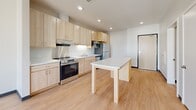 Located at 2260 Bohland Ave in Saint Paul, Minnesota, this one-bedroom, one-bathroom unit offers a practical and well-designed single-floor layout. The open-concept kitchen and living area serves as the heart of the space, featuring light maple cabinetry extending to the ceiling for generous storage, a white quartz island that doubles as a dining surface, and a full suite of stainless steel appliances including a refrigerator, electric range, built-in microwave, and dishwasher. Recessed lighting illuminates the kitchen, which is finished with light hardwood-style flooring that adds warmth and continuity throughout the main living area. The bedroom is carpeted for comfort and features neutral walls, bold dark baseboards, and a dedicated closet with built-in shelving for organized storage. A secondary closet provides additional storage within the unit. The bathroom is thoughtfully appointed with light wood vanity cabinetry, a tall storage tower, a large wall mirror, and clean tile flooring, creating a bright and functional space. Recessed lighting and a well-designed ventilation system are consistent throughout. The overall aesthetic is clean, modern, and functional, making efficient use of every square foot.