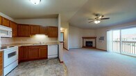 Located on Blue Heron Blvd in Fond du Lac, Wisconsin, this single-floor unit offers a well-designed, open-concept layout that maximizes both functionality and comfort. The living and kitchen areas flow seamlessly together, creating a spacious, connected feel. The living room is highlighted by a vaulted ceiling with a ceiling fan, a tile-surround fireplace serving as a central focal point, and a wall-mounted air conditioning unit. Sliding glass doors lead to a private balcony, allowing natural light to fill the space and providing outdoor views of the surrounding neighborhood.

The kitchen is outfitted with warm oak cabinetry, a full suite of white appliances including a refrigerator, electric range, and microwave, along with a double sink and tile-pattern flooring. A pantry closet adjacent to the kitchen adds convenient storage. A peninsula counter separates the kitchen from the main living area, enhancing the open layout while providing additional workspace.

The bedrooms are carpeted and generously sized. One bedroom features a ceiling fan, a closet, and sliding glass doors to the balcony. Another bedroom includes a walk-in closet with built-in shelving. A third room offers a bright window and baseboard heating. The bathroom includes a tub/shower combination, a vanity with storage, and tile-pattern flooring, completing this practical and comfortable single-level home.