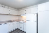 Located at 425 Park Blvd in Ogden, Utah, this two-bedroom, one-bathroom residence offers a thoughtfully organized single-floor layout. The living area features light-toned luxury vinyl plank flooring and a textured ceiling, with a large window that invites generous natural light and creates a bright, open atmosphere. The kitchen is efficiently designed with white cabinetry extending to the ceiling for ample storage, a double-basin sink, laminate countertops, and white appliances including a range, dishwasher, and full-size refrigerator — all set on durable wood-look flooring. A connecting hallway links the main living areas to the bedrooms, each finished with neutral wall-to-wall carpeting and windows that allow natural light to filter in. The primary bedroom offers a comfortable footprint with access to a dedicated closet. The second bedroom mirrors a similar design and benefits from its own closet. The shared bathroom features wood-look flooring, a tiled tub-shower combination, and clean white fixtures. Throughout the space, a consistent neutral color palette of warm beige tones and white trim contributes to a cohesive, understated aesthetic.