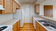Located at 1900 W Alexis Rd in Toledo, Ohio, this single-floor unit offers a practical and comfortable layout designed for everyday living. The open-concept living and dining area is carpeted and bathed in natural light, with a ceiling fan overhead and direct views into the kitchen through a breakfast bar-style pass-through. The front entry opens directly into this spacious common area, creating a welcoming and accessible flow throughout the unit. The galley-style kitchen features warm oak cabinetry, light countertops, a stainless steel sink, and white appliances including a refrigerator and dishwasher. Durable wood-look flooring runs throughout the kitchen, and a bifold-door closet provides additional pantry or storage space. The bedrooms are generously sized, each finished with plush wall-to-wall carpet, ceiling fans with light fixtures, and windows that bring in ample natural light and outdoor views. The full bathroom is cleanly appointed with a wide vanity, white cabinetry, a large mirror with overhead lighting, and a tiled shower-tub combination with chrome fixtures and safety grab bars. Overall, the unit presents a neutral, well-maintained interior that is functional and move-in ready.