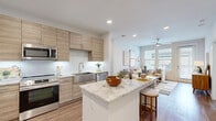 Located in Cypress, TX, this thoughtfully designed 2-bedroom, 2-bathroom residence offers a modern aesthetic with high-quality finishes throughout its well-utilized single-floor layout. The open-concept living area is bathed in natural light from large windows and features warm wood-style flooring, a ceiling fan, and direct access to an outdoor balcony, creating an inviting and airy ambiance.

The kitchen is a standout centerpiece, showcasing light wood cabinetry extending to the ceiling, a granite-topped island with bar seating, stainless steel appliances including a refrigerator, range, microwave, and dishwasher, along with a sleek subway tile backsplash and stainless steel sink.

The primary bedroom is generously sized, offering a ceiling fan and ample natural light. Its ensuite bathroom features dark cabinetry contrasted by a granite vanity countertop and a large mirror, conveying an elegant, modern feel. A second bathroom includes a soaking tub with a stylishly patterned tile surround. Both bedrooms are accompanied by dedicated walk-in closets equipped with built-in shelving and hanging rods, providing excellent storage. Wood-style flooring runs seamlessly throughout every room, tying the entire space together with a clean, contemporary look.