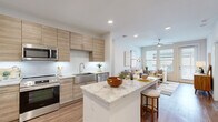 Located in Cypress, TX, this thoughtfully designed 2-bedroom, 2-bathroom residence offers a modern aesthetic with high-quality finishes throughout its well-utilized single-floor layout. The open-concept living area is bathed in natural light from large windows and features warm wood-style flooring, a ceiling fan, and direct access to an outdoor balcony, creating an inviting and airy ambiance.

The kitchen is a standout centerpiece, showcasing light wood cabinetry extending to the ceiling, a granite-topped island with bar seating, stainless steel appliances including a refrigerator, range, microwave, and dishwasher, along with a sleek subway tile backsplash and stainless steel sink.

The primary bedroom is generously sized, offering a ceiling fan and ample natural light. Its ensuite bathroom features dark cabinetry contrasted by a granite vanity countertop and a large mirror, conveying an elegant, modern feel. A second bathroom includes a soaking tub with a stylishly patterned tile surround. Both bedrooms are accompanied by dedicated walk-in closets equipped with built-in shelving and hanging rods, providing excellent storage. Wood-style flooring runs seamlessly throughout every room, tying the entire space together with a clean, contemporary look.
