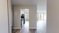 This single-floor residence offers four bedrooms and one bathroom within a thoughtfully arranged layout. Light-toned luxury vinyl plank flooring runs throughout, providing a cohesive and easy-to-maintain foundation across all rooms. Neutral warm-grey walls and crisp white trim create a clean, contemporary aesthetic throughout the space.

The galley-style kitchen is efficiently designed with white shaker cabinetry, light granite-look countertops, a stainless steel sink, and stainless steel appliances including a refrigerator and range. The kitchen opens toward the living area, promoting a connected feel between cooking and entertaining spaces.

The living room is generously proportioned and filled with natural light, courtesy of large windows and a sliding glass door that leads to a balcony with outdoor views. Baseboard heating units line the walls, ensuring consistent warmth throughout.

The four bedrooms are each finished with the same light flooring and neutral palette, offering versatile, functional spaces. Several bedrooms feature windows with blinds that frame views of surrounding greenery and neighbourhood rooftops. The primary bedroom provides a comfortable and well-sized retreat.

The bathroom is clean and practical, featuring a full tub-shower surround, toilet, and a vanity with a granite-look countertop, all finished in bright white tones. Textured ceilings are present in select areas, adding a subtle architectural detail throughout this well-maintained residence.