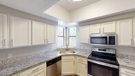 Located at 1111 N Mission Park Blvd in Chandler, AZ, this single-story, three-bedroom, one-bathroom home offers a well-organized layout designed for comfortable everyday living. The living area features rich wood-look flooring, neutral-toned walls, and a ceiling fan with light fixture, creating a bright and airy atmosphere. A glass door with an arched transom window floods the space with natural light and provides access to an outdoor area. The kitchen is a functional highlight, showcasing granite countertops, crisp white cabinetry, and a full suite of stainless steel appliances including a range, over-the-range microwave, and dishwasher. A corner sink positioned beneath dual windows invites natural light into the cooking space. The generously sized primary bedroom is carpeted, includes a ceiling fan, and features sliding glass doors with vertical blinds opening to an outdoor patio. The additional bedrooms offer wood-look flooring and large windows that bring in ample daylight. The bathroom is clean and well-appointed, with a wide vanity, large mirror, white cabinetry, and a full tub-shower combination. Wood-look flooring extends throughout the bathroom, tying the home's design together cohesively.
