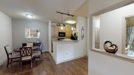 This single-story residence offers a thoughtfully designed layout that balances functionality with comfortable living. The living room serves as the heart of the home, featuring rich dark wood-look flooring, neutral walls, and a ceiling fan overhead. A pair of French doors floods the space with natural light while providing outdoor access, and the open arrangement accommodates both lounging and entertaining areas with ease.

The galley-style kitchen is well-equipped with light wood cabinetry extending to the ceiling for ample storage, black appliances including a range, built-in microwave, refrigerator, and dishwasher, and a double stainless steel sink. Light tile flooring runs underfoot, and a pass-through breakfast bar with pendant lighting connects the kitchen to the adjacent dining area, which features matching wood-look flooring.

The primary bedroom offers plush carpeting and a spacious closet, maintaining a calm, neutral palette. The secondary bedroom features a striking teal accent wall, a walk-in closet, and a window that draws in natural light. The full bathroom includes a single-sink vanity with light wood cabinetry, a tiled tub-shower combination, and tile flooring, completing this cohesive and practical residence.