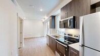 Located at 144 25th St in Ogden, Utah, this efficiently designed studio unit offers a well-planned single-floor layout that maximizes every square foot. The kitchen is a standout feature, showcasing rich dark wood cabinetry with sleek hardware, a white quartz countertop, undermount sink, and a full suite of stainless steel appliances including a refrigerator, electric range, microwave, and dishwasher. A window above the sink fills the kitchen with natural light and connects visually to the surrounding streetscape. Light-toned hardwood-style flooring runs throughout the entire unit, creating a cohesive and warm aesthetic. The open living area is bright and airy, with recessed lighting and clean white walls that enhance the sense of space. Large sliding glass doors lead to a private balcony, offering views of the neighboring historic brick architecture and allowing abundant natural light to pour in. The bathroom is clean and functional, featuring a tub-shower combo with built-in shelving, a wood-toned vanity with a white countertop, and consistent flooring that ties the space together. This unit delivers a modern, move-in-ready interior in a well-situated Ogden location.