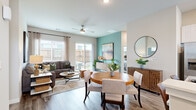 This single-floor residence is designed with a thoughtful open-concept layout that seamlessly connects the living, dining, and kitchen areas. Wood-look plank flooring runs throughout the main living spaces, providing a cohesive and contemporary foundation. The living room is bright and inviting, anchored by large windows and a sliding glass door that opens directly to a private outdoor patio, offering a functional extension of the interior living space. A ceiling fan overhead adds both practicality and a finishing touch to the room.

The dining area is distinguished by a warm amber accent wall that adds visual depth and contrast to the otherwise neutral color palette. An adjacent teal accent wall in the living area further contributes to the home's personality. The kitchen features white shaker-style cabinetry, granite countertops, a stainless steel appliance suite including a refrigerator, range, microwave, and dishwasher, along with a peninsula that provides additional seating and prep space.

The bedroom is comfortably sized with ample natural light from a large window fitted with blinds and curtains. The bathroom includes a granite-topped vanity with white cabinetry and a glass-enclosed walk-in shower with tile surround. Overall, the space presents a clean, modern aesthetic with well-chosen design details.