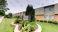 Midvale Heights Apartments is a well-established residential community that combines classic architectural design with thoughtfully maintained outdoor surroundings. The building exterior showcases a timeless combination of brick and neutral-toned siding, lending the property a sturdy and inviting character. The single-floor layout provides convenient, accessible living without the need for stairs or elevators, making it an ideal choice for a wide range of residents. The community's curb appeal is immediately evident through its carefully tended landscaping, which features a variety of colorful flowering plants, neatly trimmed shrubs, and mature evergreen trees that frame the entrance with natural beauty. A prominently placed community sign at the entrance reinforces the property's established identity and neighborly atmosphere. The grounds are kept in excellent condition, with lush green lawns and decorative garden beds that contribute to a serene and welcoming environment. The overall ambiance of Midvale Heights Apartments strikes a balance between suburban tranquility and functional design, offering residents a comfortable and attractive place to call home within a community that clearly takes pride in its presentation and upkeep.