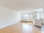 Located at 390 Boul de la Côte-Vertu in Montréal, this well-laid-out unit offers four bedrooms and one bathroom across a single floor. The open-concept living and dining area is immediately welcoming, characterized by classic light-toned parquet flooring that runs throughout the space. Large windows allow generous natural light to pour in, offering views of the surrounding neighbourhood and creating a bright, airy atmosphere. Baseboard heating is present throughout, ensuring comfort year-round.

The kitchen is clean and functional, featuring white cabinetry, white subway tile backsplash, a peninsula counter, and light tile flooring. It is equipped with a stainless steel refrigerator and stove, making it fully move-in ready. The four bedrooms are well-proportioned, each benefiting from windows with neighbourhood views and the same warm parquet flooring found in the main living area. The primary bedroom offers a generous amount of space suitable for a full bedroom suite.

The bathroom is finished with large-format light tiles, a white vanity with storage, and a full bathtub-shower combination with tile surround. The overall aesthetic of the unit is clean and neutral, with white walls throughout providing a versatile canvas. A hallway connects the rooms efficiently, contributing to a practical and cohesive floor plan.