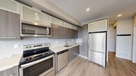 This thoughtfully designed 2-bedroom, 2-bathroom unit in Calgary, AB offers a modern and functional layout across a single floor. The open-concept living, dining, and kitchen area serves as the heart of the home, finished with light wood-look laminate flooring that flows seamlessly throughout. The contemporary kitchen is well-appointed with two-tone cabinetry featuring wood-grain lower cabinets and frosted glass upper cabinets, a white subway tile backsplash, light quartz countertops, and a full suite of stainless steel appliances including a range, over-the-range microwave, dishwasher, and refrigerator. A dedicated entrance provides a welcoming arrival experience, while a hallway connects the private areas of the unit. Both bedrooms are finished in neutral tones with the same laminate flooring, and the primary bedroom benefits from a closet with wire shelving. The two bathrooms are finished with wood-grain cabinetry, quartz vanity tops, large mirrors, and a soaker tub with shower. Additional conveniences include in-unit laundry and a private balcony accessible from the living area, equipped with a wall-mounted air conditioning unit for year-round comfort.