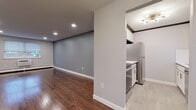 Located on Sunset Rock in Plainville, CT, this single-floor residence has been thoughtfully updated with contemporary finishes while maintaining a clean, functional layout. Rich hardwood flooring flows throughout the main living areas, complementing the neutral gray walls and crisp white trim to create a cohesive, modern aesthetic.

The open living area is generously proportioned, offering flexible space bathed in recessed lighting and natural light from strategically placed windows. A half-wall partition separates the living space from the kitchen, maintaining an open feel while defining each zone. The galley-style kitchen is well-appointed with white shaker cabinetry accented by gold hardware, white subway tile backsplash, white quartz countertops, and stainless steel appliances including a refrigerator, dishwasher, and range. Light stone-look tile flooring ties the kitchen together seamlessly.

The bedroom features warm hardwood floors, a window with natural light, baseboard heating, and access to two separate closets via paneled white doors. The bathroom is finished with large-format marble-look tile on the tub surround and floor, a soaking tub, and a window for natural ventilation. Baseboard heating is present throughout, ensuring year-round comfort.