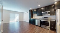Located at 500 Bank St in New London, Connecticut, this single-floor residence offers a thoughtfully designed layout with modern finishes throughout. The open-concept living and kitchen area is anchored by rich hardwood-style flooring that flows seamlessly from room to room, creating a cohesive and welcoming atmosphere.

The kitchen is a standout feature, equipped with a full suite of stainless steel appliances including a refrigerator, electric range, over-the-range microwave, and dishwasher. Dark espresso cabinetry extends from floor to ceiling, providing generous storage, while granite-look countertops add a refined touch. Recessed lighting illuminates the space efficiently.

The living area is bright and open, benefiting from natural light that pours in through sliding glass doors leading to an outdoor access point. A wall-mounted mini-split unit provides climate control. A stylish sliding barn door serves as a distinctive architectural accent, adding character to the interior.

The bathroom features classic black-and-white hexagonal tile flooring, a dark vanity with a white countertop, and a large mirror. A dedicated utility area houses a State ProLine commercial-grade electric water heater. The unit also includes closet space and multiple entry points, contributing to its functional and well-organized design.
