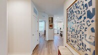 This thoughtfully designed 2-bedroom, 2-bathroom residence offers a cohesive, single-floor layout that maximizes both functionality and comfort. Light wood flooring flows seamlessly throughout, unifying the open-concept living spaces with a warm, contemporary aesthetic.

The kitchen is a standout feature, outfitted with crisp white shaker cabinetry, quartz countertops, a subway tile backsplash, stainless steel appliances, and a central island with bar seating. Pendant lighting and a large window fill the space with natural light, making it as inviting as it is practical.

The open living room is anchored by a bank of oversized windows dressed with sheer white curtains and wood blinds, flooding the room with daylight and creating an airy, comfortable atmosphere. A ceiling fan adds to the functionality of this well-lit gathering space.

The primary bedroom offers a quiet retreat with natural light filtering through large windows, while the second bedroom features a distinctive accent wall in soft blue, ceiling fan, and generous window exposure. Both bedrooms are well-proportioned and relaxing in character.

The bathrooms are finished with white vanity cabinetry, quartz countertops, and wood-look flooring. One bath includes a glass-enclosed walk-in shower with white tile surround and built-in shelving. A hallway with closet storage completes the efficient floor plan.
