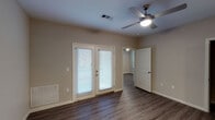 This single-story, two-bedroom, two-bathroom residence offers a functional and modern layout designed for comfortable everyday living. Wood-look plank flooring extends throughout the main living areas and bedrooms, providing a cohesive aesthetic across the unit.

The kitchen is a standout feature, designed in a galley style with dark espresso cabinetry lining both sides, light granite-style countertops, and black appliances including a range, microwave, and refrigerator. A peninsula with seating overhang connects the kitchen to the open living area, which is outfitted with a ceiling fan and offers a seamless flow between spaces.

The living area features French doors that invite natural light and provide outdoor access. Each bedroom is equipped with a ceiling fan and connects to the surrounding hallway. The bathrooms are finished with tile flooring, dark vanity cabinetry, white countertops, and a tub-shower combination. Neutral wall tones are carried throughout, contributing to a clean, move-in-ready atmosphere.

A dedicated in-unit laundry area with washer hookups adds convenience, while a panel door separates it from the main living space, maintaining an organized and tidy layout.